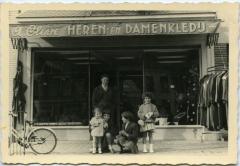 Familie poseert voor stoffen- en kleerwinkel A. Cleve 