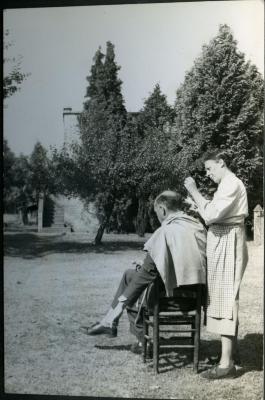 Marie Minne knipt het haar van Edgar Gevaert in de tuin